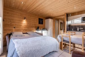 a bedroom with a bed and a table and a kitchen at La Duche 101 in Le Grand-Bornand