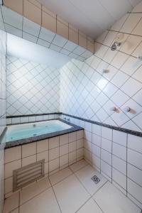 een badkamer met een hot tub in een wit betegelde kamer bij Hotel GAPH Maringa - Economico Mini Resort in Maringá