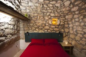 una camera con un letto rosso in una parete in pietra di Trullo in the Wood a Nardò