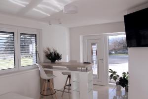a white kitchen with a counter and a table and chairs at Deluxe Apartments Panorama in Lesce
