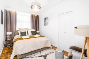 a white bedroom with a large bed with green pillows at Main Square Apartments by LoftAffair in Krakow