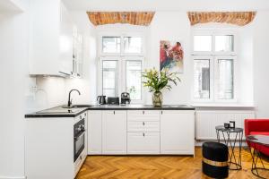 una cocina con armarios blancos y una silla roja en Main Square Apartments by LoftAffair, en Cracovia