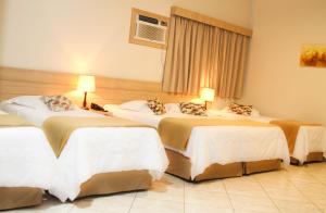 a hotel room with three beds in a room at Hotel Fazenda Pirâmides in Atibaia