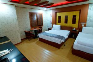 una camera d'albergo con 2 letti, una scrivania e un tavolo di Goryeo Hotel a Andong