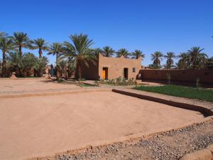 a house in the middle of a desert with palm trees at sahara desert camp tours in Zagora