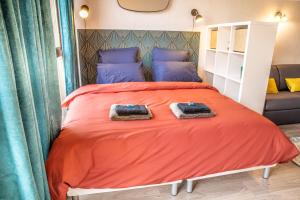 a bedroom with an orange bed with two towels on it at Grand Studio Stan Nancy - calme, cosy, lumineux in Nancy