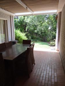a patio with a wooden table and chairs on a porch at CREDO Guest House in Bloemfontein