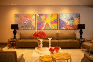 a living room with a couch and paintings on the wall at Hotel Florença in Americana