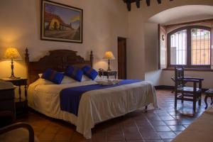 a bedroom with a large bed with blue pillows at Hotel Posada de Don Rodrigo Antigua in Antigua Guatemala