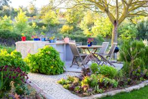 a patio with a table and chairs in a garden at Casa do Mundo in Calhariz
