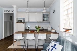 een keuken met witte kasten en een tafel en stoelen bij Sanhaus Apartments - Apartamenty Capri in Sopot