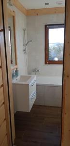 een badkamer met een wastafel, een bad en een raam bij NowiNowe Domki in Dzianisz
