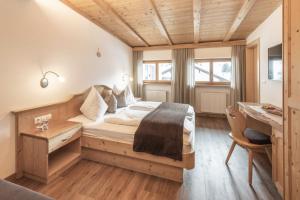 a bedroom with a large bed and a desk at Villa David Dolomites in Selva di Val Gardena