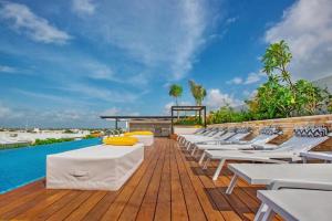 a row of white lounge chairs on a deck next to a pool at Menesse the City by Casago in Playa del Carmen