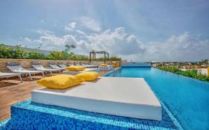 a bedroom with yellow pillows and a swimming pool at Menesse the City by Casago in Playa del Carmen