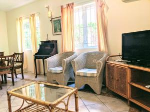 ein Wohnzimmer mit Stühlen, einem TV und einem Klavier in der Unterkunft TopHome Gold Coast in Flic-en-Flac