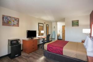 Habitación de hotel con cama y escritorio con TV. en Econo Lodge, en Cedar Rapids