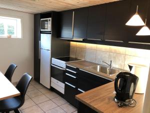 a kitchen with black cabinets and a sink at Skagentoppen Rooms in Skagen