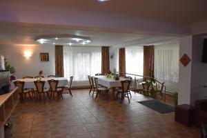 une salle à manger avec des tables et des chaises blanches dans l'établissement Pensiunea Steluta, à Predeal