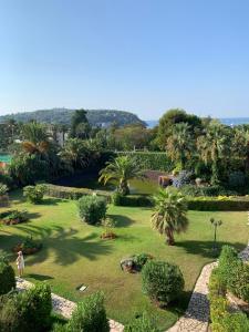 una persona parada en un jardín con palmeras en Appartement agréable en bord de mer, en Villefranche-sur-Mer