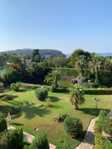 a person standing in a garden with palm trees at Appartement agréable en bord de mer in Villefranche-sur-Mer