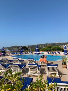 Un hombre sentado en una silla junto a una piscina. en Appartement agréable en bord de mer, en Villefranche-sur-Mer
