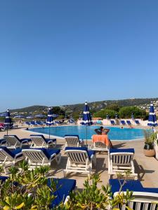 a man sitting in a chair next to a swimming pool at Appartement agréable en bord de mer in Villefranche-sur-Mer