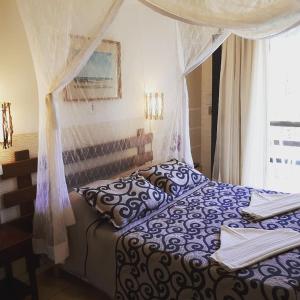 a bedroom with a bed with a canopy and a window at Hotel La Brise in Cabo Frio
