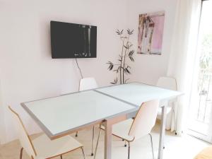 mesa blanca con sillas y TV en la pared en Enric Granados 15, en Barcelona