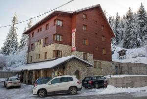 een groot gebouw met auto's geparkeerd voor het bij Hotel Snješko in Jahorina