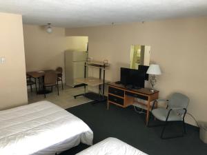 Habitación de hotel con cama y escritorio con TV. en Jockey Motel en Edmonton