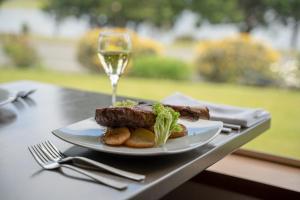 einen Teller mit Essen und ein Glas Wein auf dem Tisch in der Unterkunft Kingsgate Hotel Te Anau in Te Anau