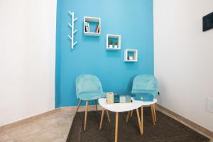 duas cadeiras e uma mesa em frente a uma parede azul em B&B Vico 10 em Guspini