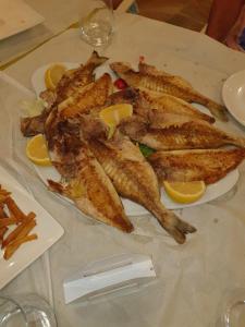 un plato de pescado con rodajas de limón en una mesa en Hotel Sarajet e Pashait 1, en Dhërmi