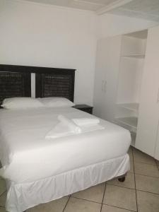 um quarto com uma grande cama branca com lençóis brancos em Lisokhanya GuestHouse em East London