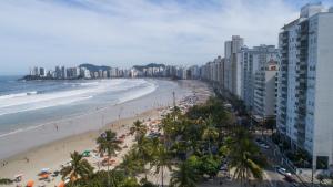 a beach with a crowd of people and the ocean at Hotel Guarumar in Guarujá