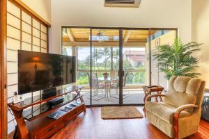 uma sala de estar com uma televisão grande e uma cadeira em Keauhou Kona Surf & Racquet Club #7-302 em Kailua-Kona