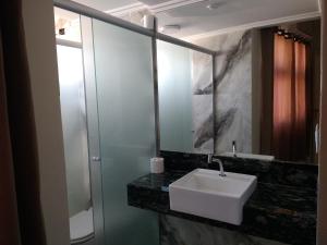 y baño con lavabo blanco y espejo. en Apart Service Araras - VPC, en Caldas Novas