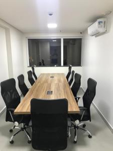 uma sala de conferências com uma mesa de madeira e cadeiras pretas em Flat no Brookfield Towers em Goiânia