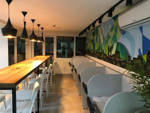 uma sala de jantar com cadeiras brancas e uma mesa longa em Flat no Brookfield Towers em Goiânia