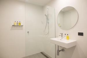 Baño blanco con lavabo y espejo en The Seabird, en Moruya
