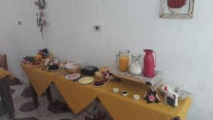 uma mesa amarela com comida e vasos em Pousada Bruluka em Tiradentes