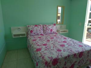 1 dormitorio con 1 cama con colcha rosada de flores en Residencial Fagundes, en Florianópolis