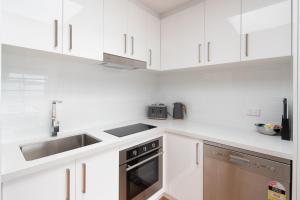 卡尔斯Phillip Island Townhouses的白色的厨房设有水槽和炉灶。