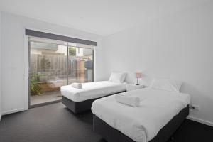 two beds in a room with a window at Phillip Island Townhouses in Cowes