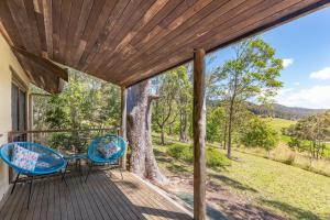 a porch with two chairs and a tree at Friday Creek Retreat in Coffs Harbour