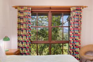 a bedroom with a bed and a window with curtains at Friday Creek Retreat in Coffs Harbour