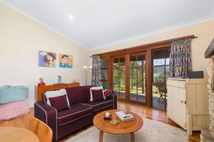 a living room with a purple couch and a table at Friday Creek Retreat in Coffs Harbour