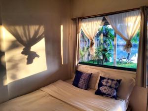 1 dormitorio con 1 cama y una ventana con cortinas en Ban Narai River Guesthouse, en Chiang Mai