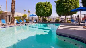 a swimming pool with blue chairs and umbrellas at SureStay Hotel by Best Western Phoenix Airport in Phoenix